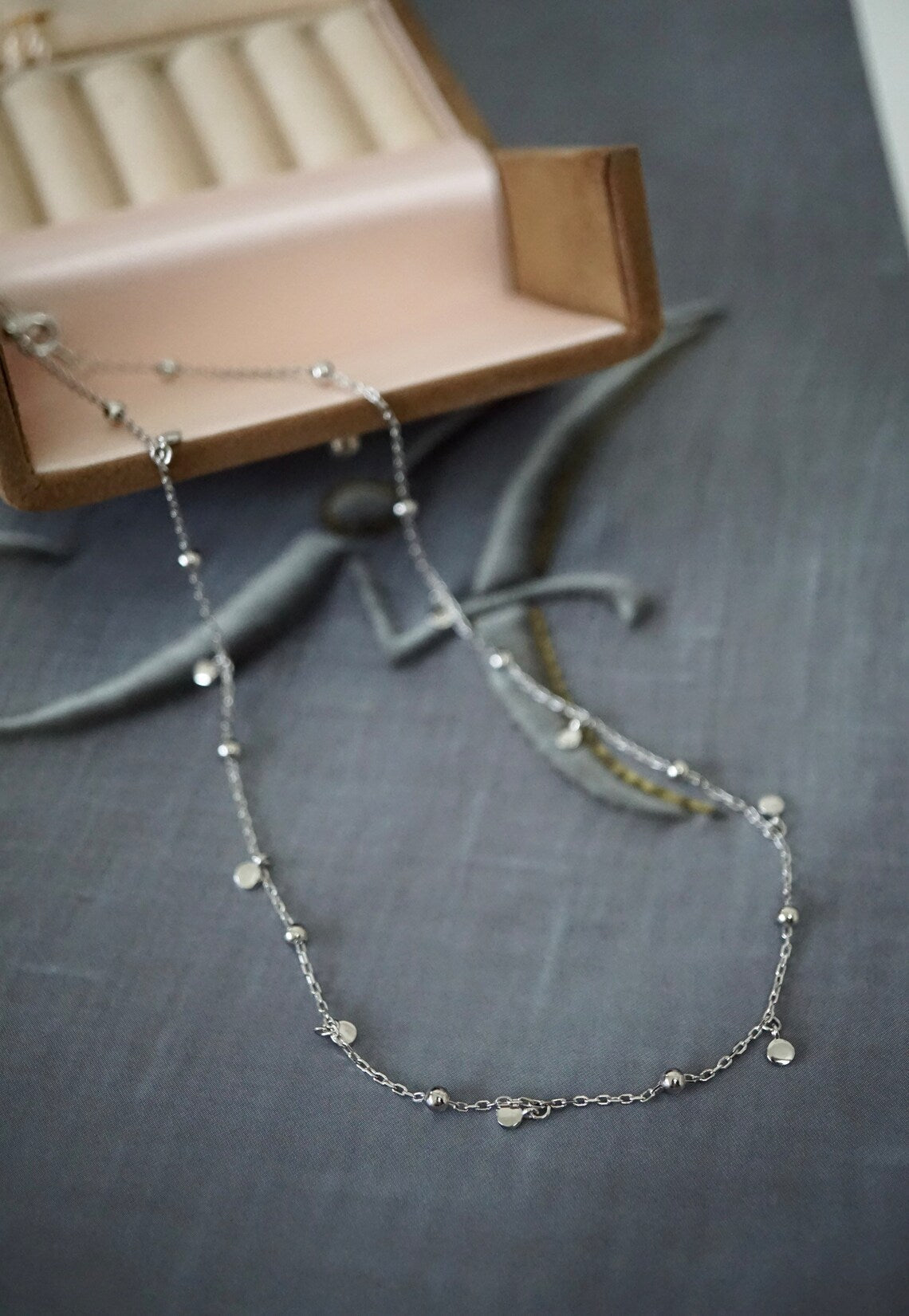 Silberne Halskette mit Anhängern, Schmuckschatulle, elegantes Design, Damenaccessoire.
