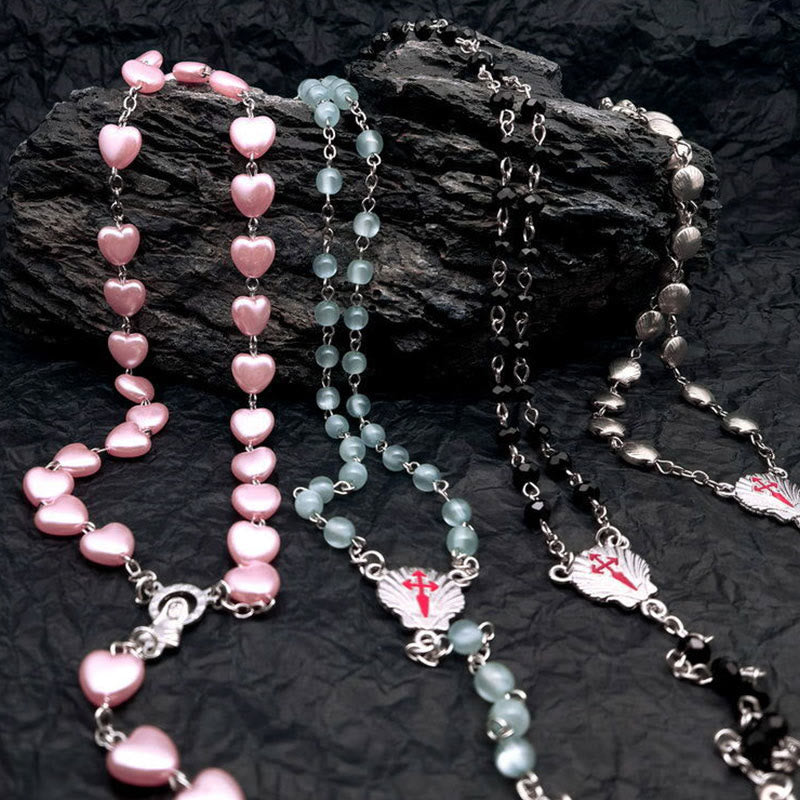 Rosenkränze mit rosa, blauen und schwarzen Perlen auf schwarzem Hintergrund, religiöser Schmuck.