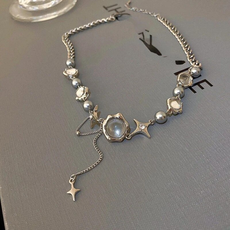 Silberne Halskette mit Perlen und Sternanhängern auf grauem Hintergrund, eleganter Schmuck.
