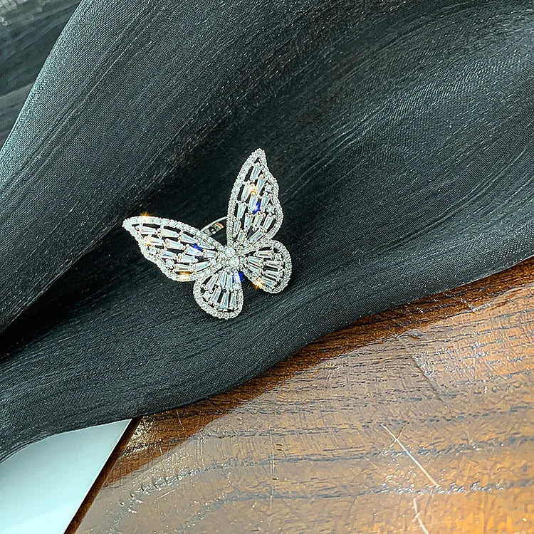 Silberner Schmetterlingsring mit Kristallen auf schwarzem Stoff, eleganter Schmuck, Damenaccessoire.