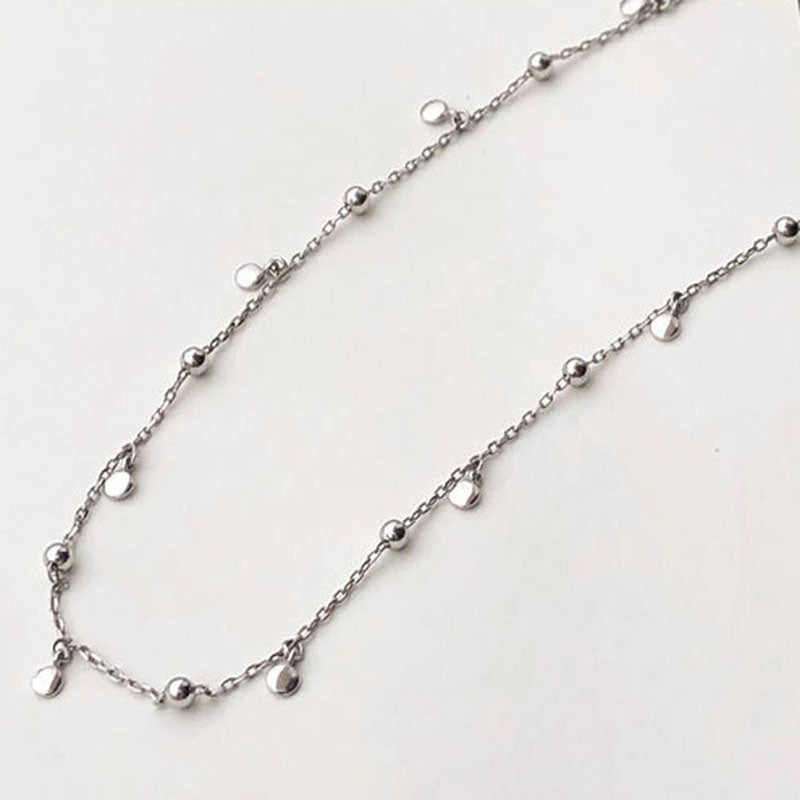 Silberne Halskette mit kleinen Kugeln und Plättchen, minimalistisches Schmuckdesign.