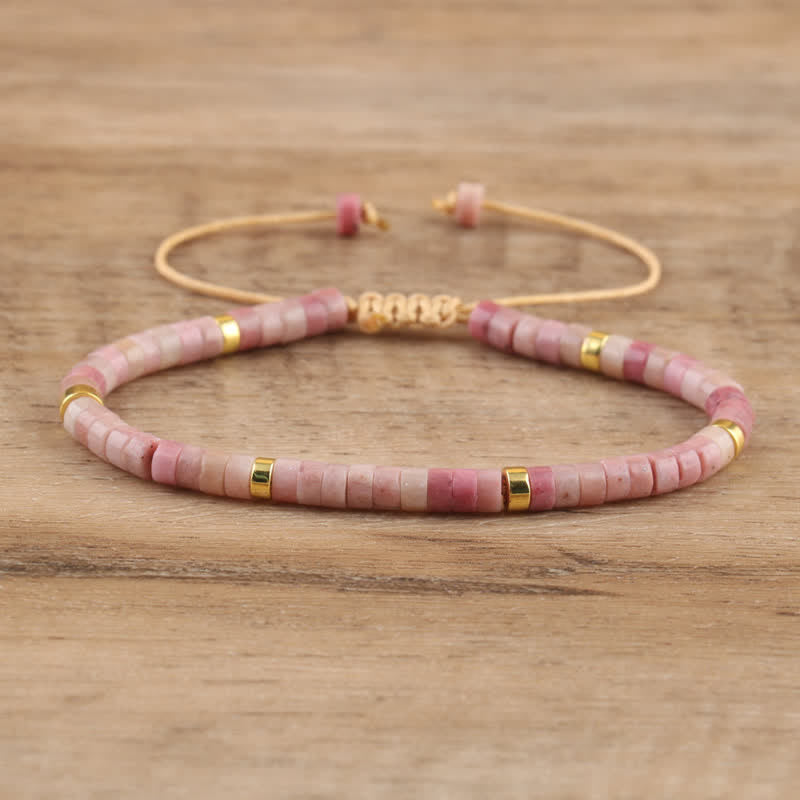 Rosa Perlenarmband mit goldenen Akzenten auf Holzoberfläche, handgefertigter Schmuck.