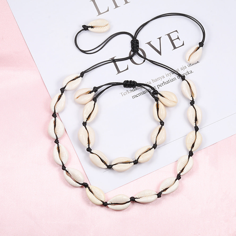 Halskette und Armband Set aus Naturmuscheln auf schwarzer Kordel, modisches Schmuckdesign.