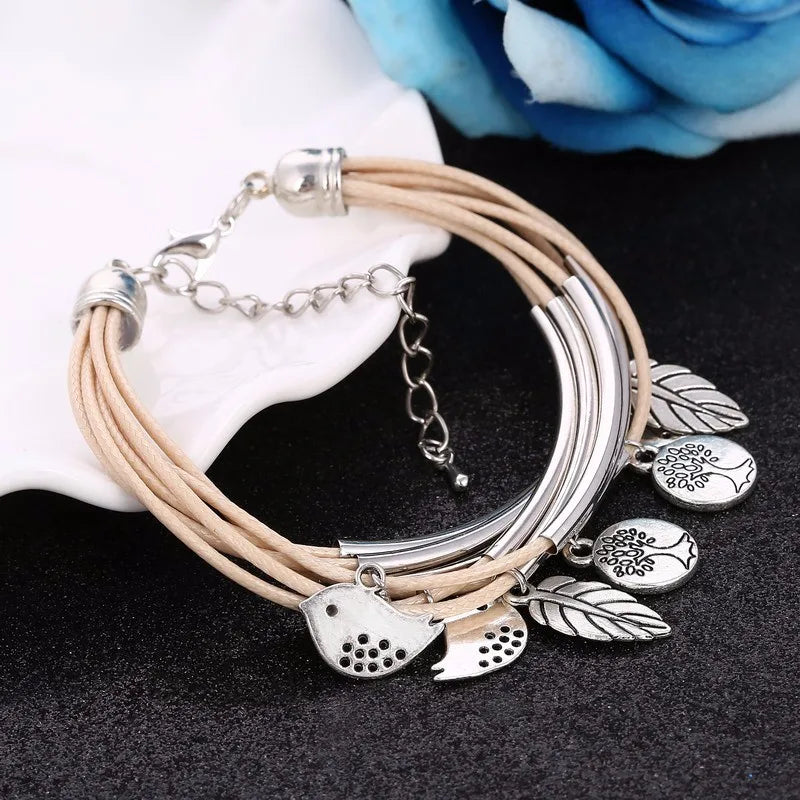 Beiges Lederarmband mit silbernen Anhängern, Blatt- und Vogelmotiv, Damenmode-Schmuck.