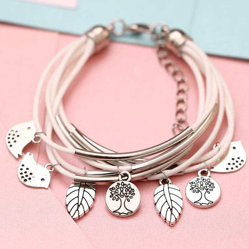 Mehrlagiges Armband mit weißen Lederbändern, silbernen Baum- und Blattanhängern, Damenmode.