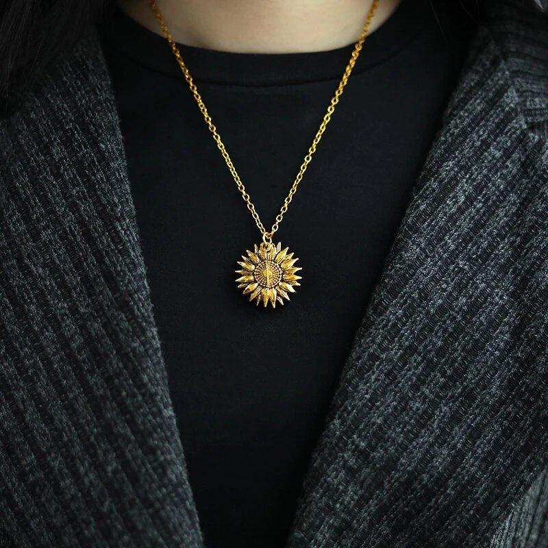 Goldene Sonnenanhänger-Halskette auf schwarzem Oberteil, eleganter Schmuck für Damen.