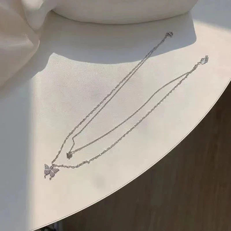 Silberne Schmetterlingskette auf weißem Tisch, eleganter Schmuck, modisches Accessoire.