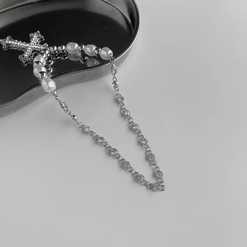 Silberne Rosenkranzkette mit Perlen und Kreuzanhänger auf grauem Hintergrund.