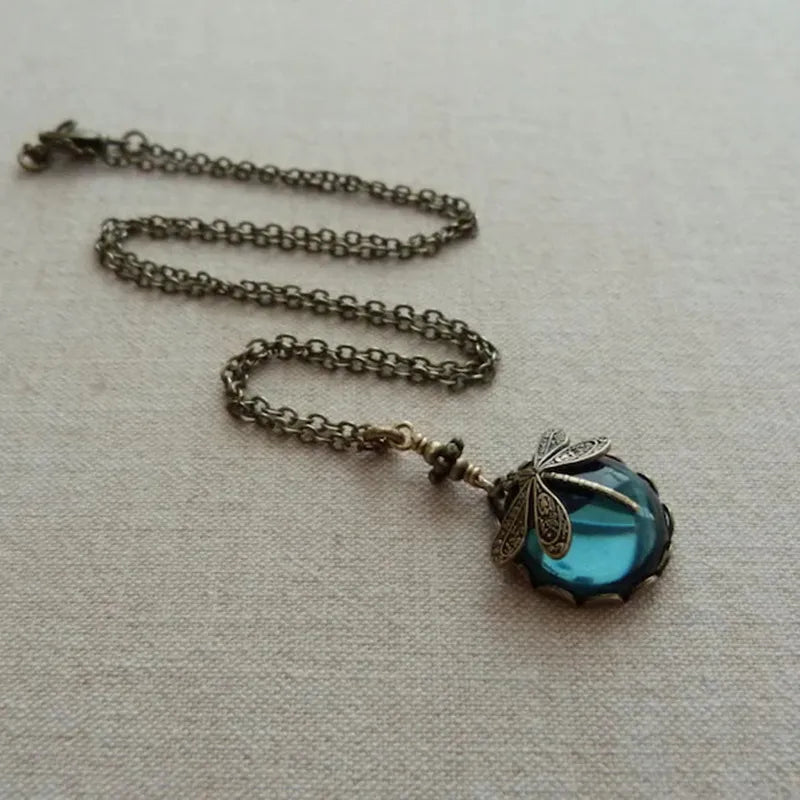Antike Halskette mit blauem Glasanhänger und Libellenmotiv, Vintage-Schmuck, Metallkette.