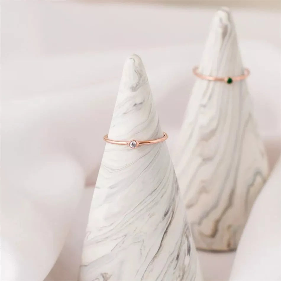 Roségoldener Ring mit Diamant auf Marmorkegel, minimalistischer Schmuck, elegantes Design.