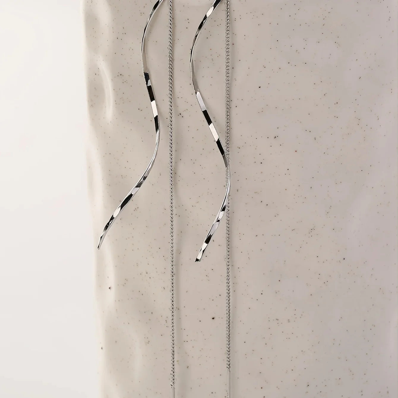 Silberne, lange Ohrringe mit schwarz-weißen Streifen auf hellem Hintergrund, minimalistisches Design.