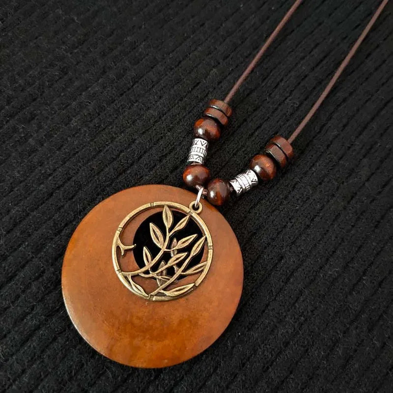 Braune Holz-Halskette mit rundem Anhänger und Blattmotiv, handgefertigt, Boho-Stil.