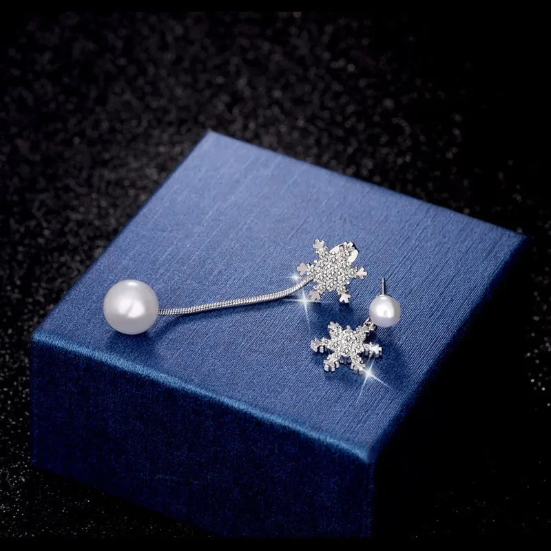 Schneeflocken-Ohrringe mit Perlen, silber, auf blauem Schmuckkästchen, elegantes Design.