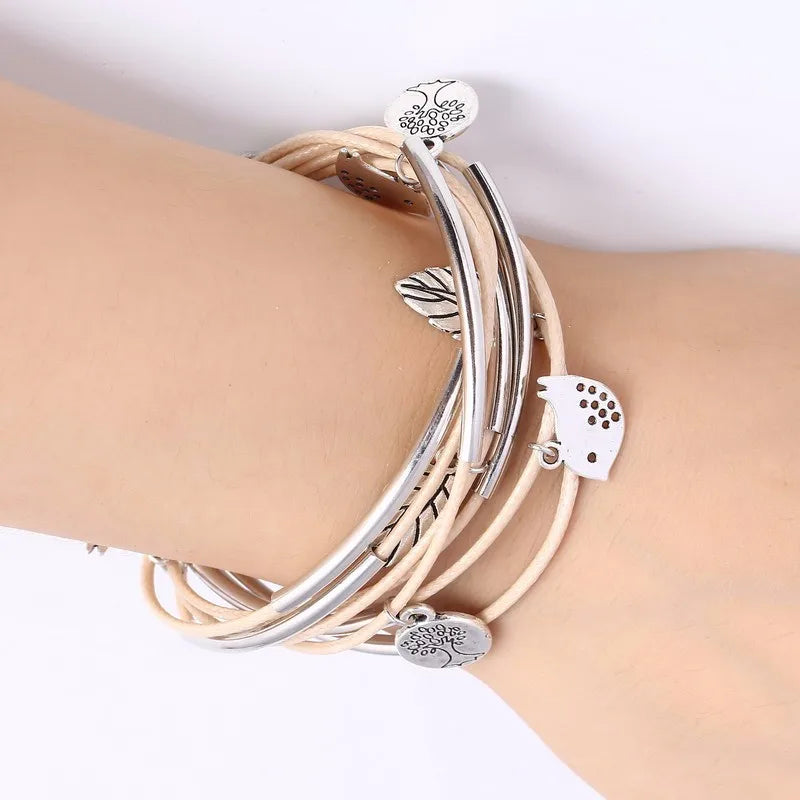 Mehrlagiges Armband, beige Leder, silberne Metallanhänger, modisches Damenaccessoire.