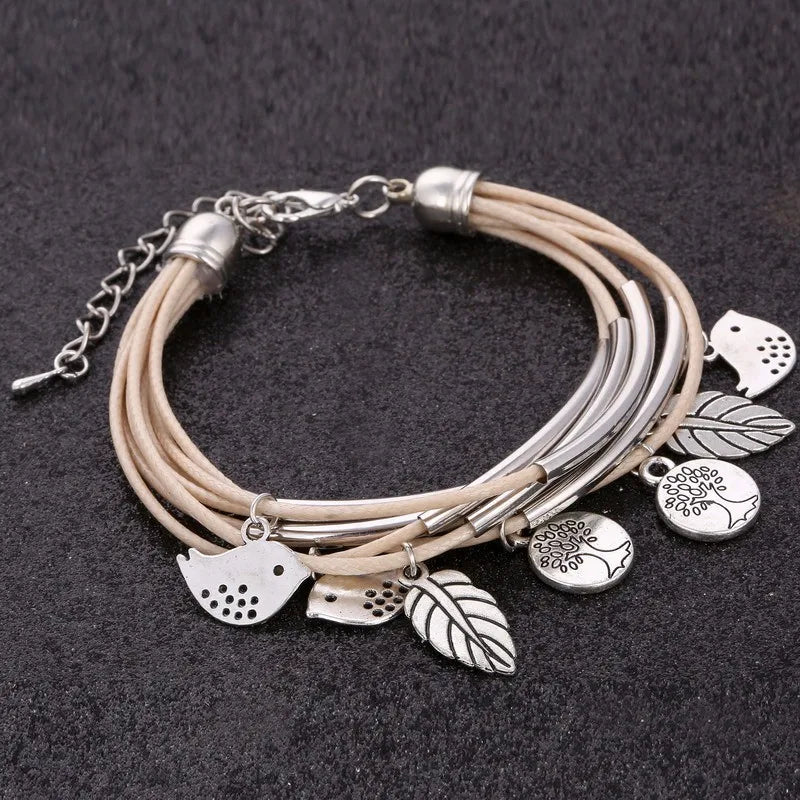 Beiges Lederarmband mit silbernen Vogel- und Blattanhängern, Damen Schmuck Accessoire.