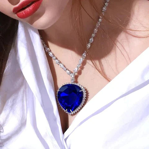 Frau mit blauem Herzanhänger, Silberkette, eleganter Schmuck, modisches Accessoire.