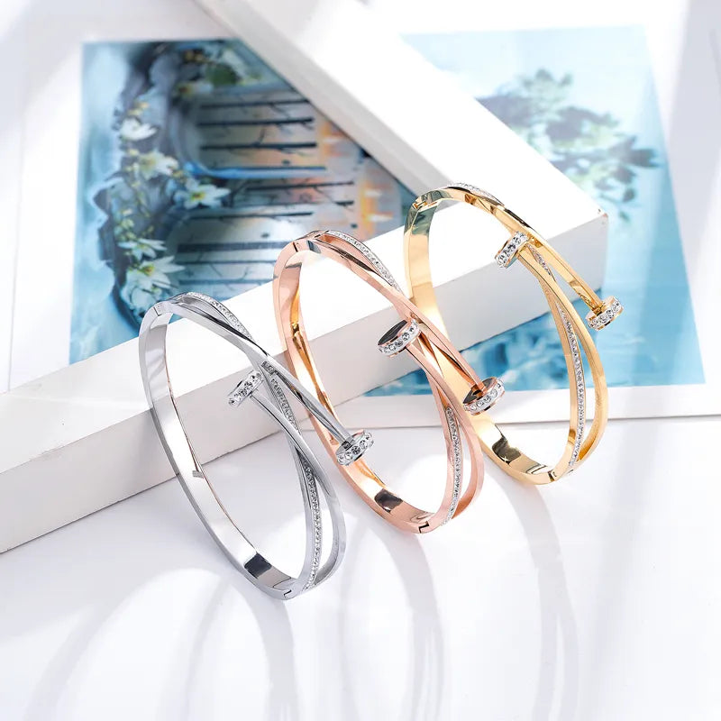 Drei elegante Armreifen in Silber, Roségold und Gold mit Kristallen auf weißem Hintergrund.