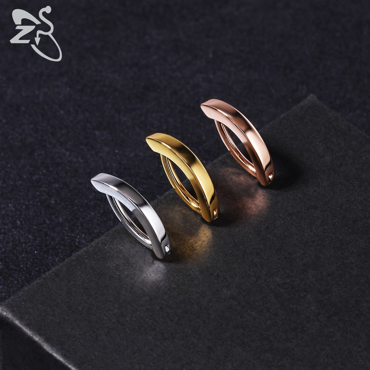 Drei minimalistische Creolen in Silber, Gold und Roségold auf schwarzem Hintergrund.