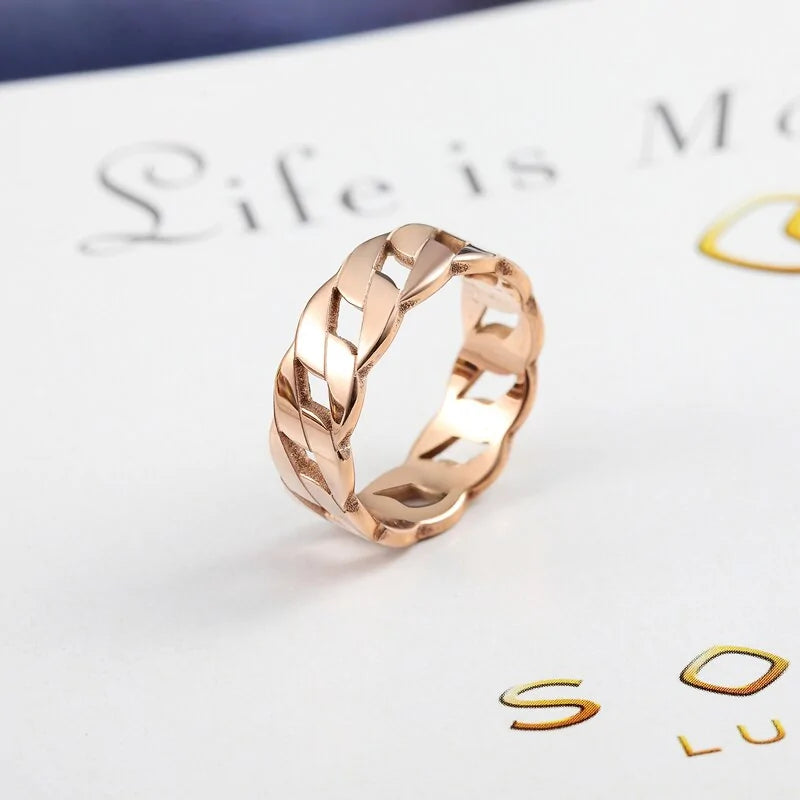 Roségoldener geflochtener Ring auf weißem Hintergrund, elegantes Schmuckdesign.