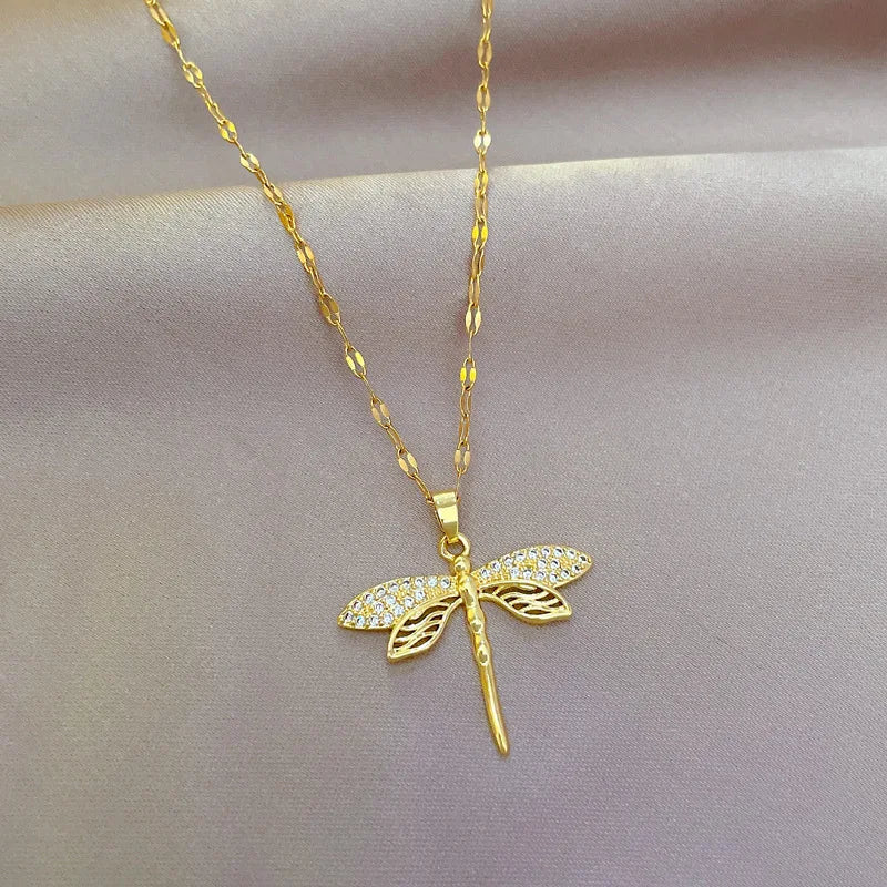 Goldene Libellen-Halskette mit Strasssteinen auf seidigem Hintergrund, eleganter Schmuck.