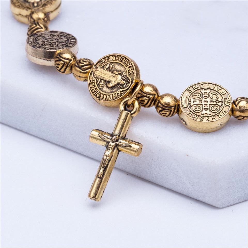 Goldenes Benediktus-Armband mit Kreuzanhänger, religiöser Schmuck, Detailansicht.