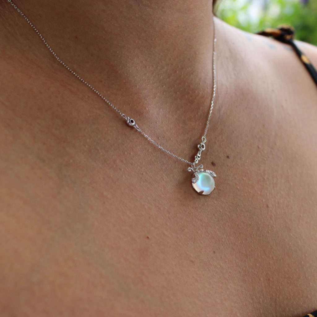 Silberne Halskette mit rundem, schimmerndem Anhänger auf Haut, eleganter Schmuck.