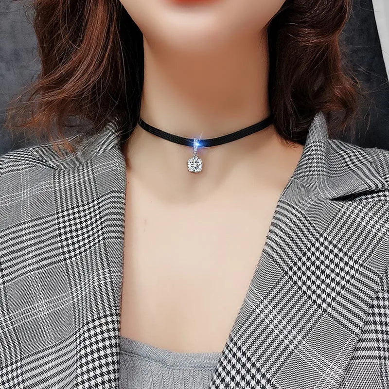Frau mit schwarzem Choker-Halskette und funkelndem Anhänger, kariertes Sakko, modisch.