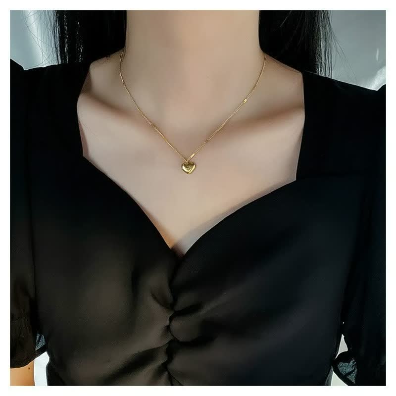 Goldene Herz-Halskette, zartes Design, Damenmode, eleganter Schmuck, schwarzes Kleid.