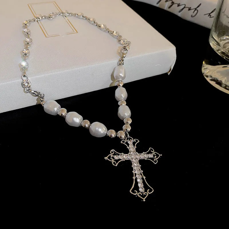 Silberne Kreuzkette mit weißen Perlen auf schwarzem Hintergrund, eleganter Schmuck.