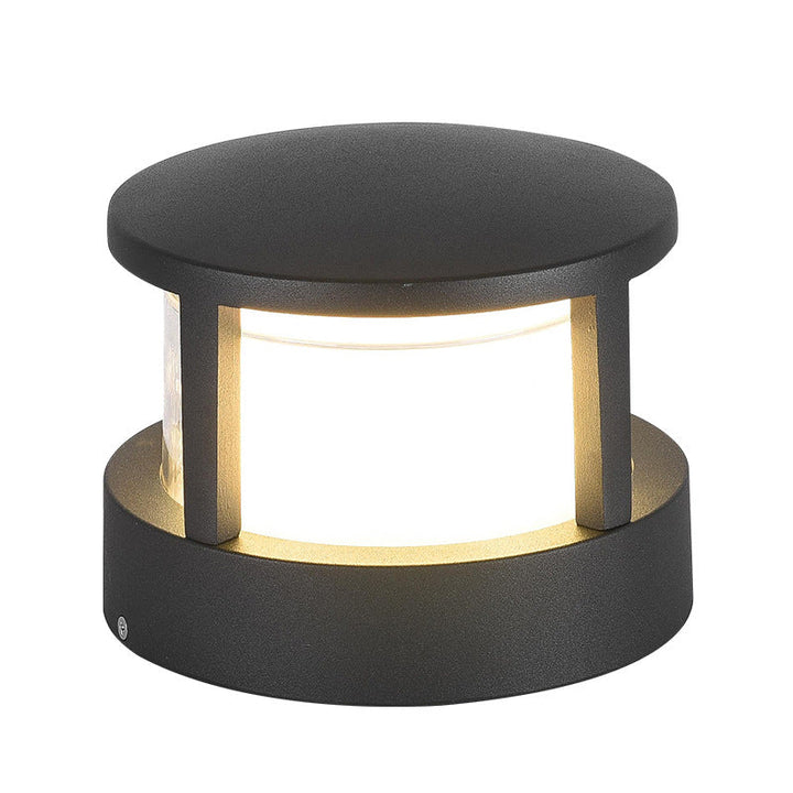 Tæt frontbillede af rund sort lampe med flad låg og oplyst hvid skærm mellem søjlerne. 12