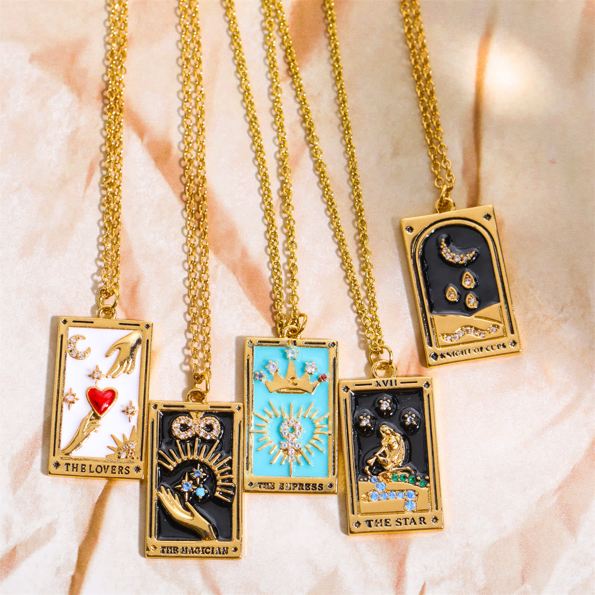 Fünf goldene Tarot-Anhänger mit Ketten, verziert mit bunten Symbolen und Edelsteinen.