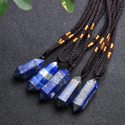 Fünf blaue Lapislazuli-Anhänger an schwarzen Kordeln auf schwarzem Hintergrund.
