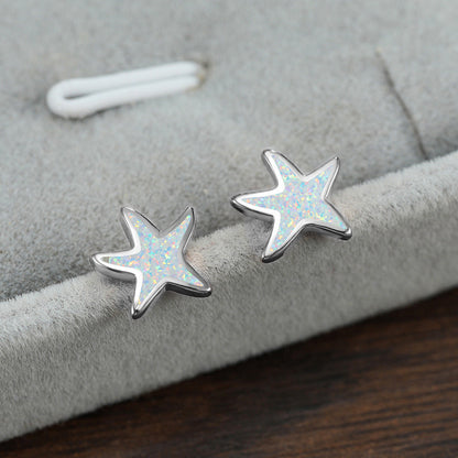 Silberne Stern-Ohrringe mit Opal-Einlage auf grauem Hintergrund, modischer Schmuck.