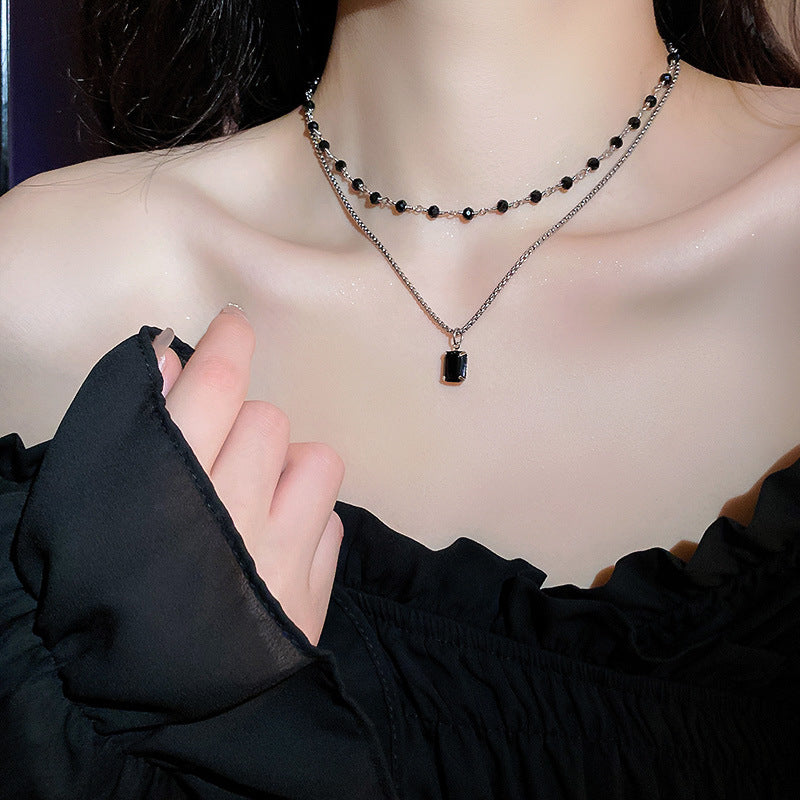 Doppelte Halskette mit schwarzem Anhänger, Damenmode, eleganter Schmuck, schwarzes Oberteil.