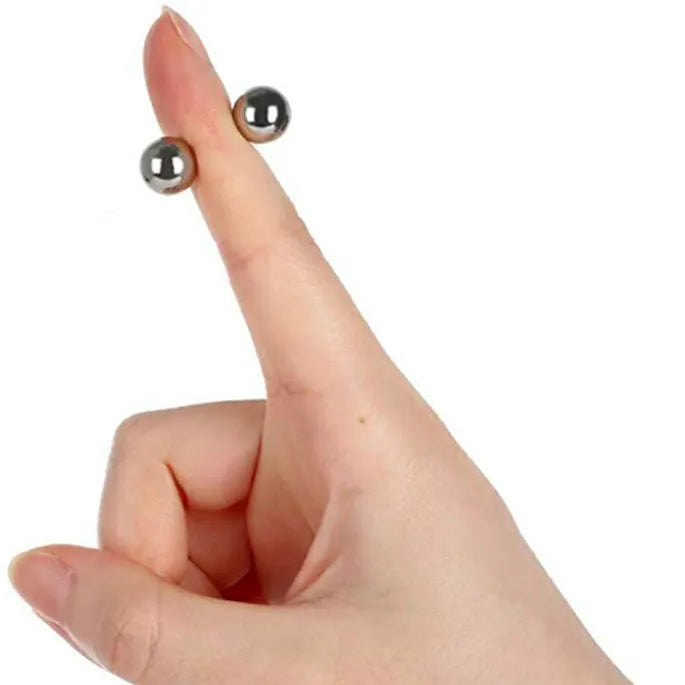 Hånd med udstrakt pegefinger, hvor to små sølvfarvede magnetkugler sidder på hver side af fingeren. 8