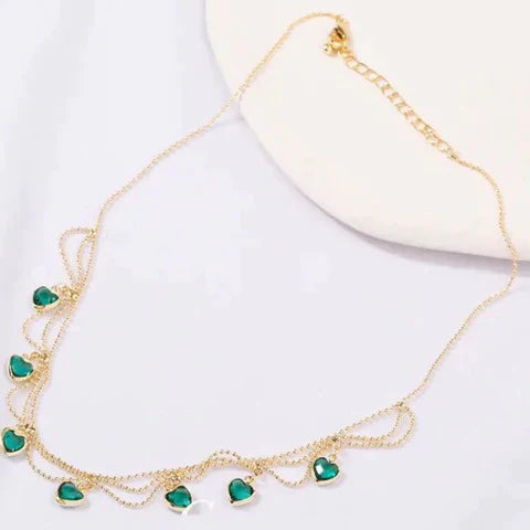 Goldene Halskette mit grünen Herzanhängern, eleganter Schmuck, Damenaccessoire.
