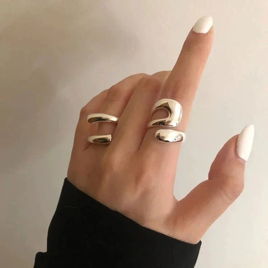 Silberner, minimalistischer Doppelring an Hand mit weiß lackierten Nägeln, modisches Accessoire.