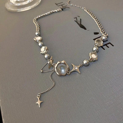 Silberne Halskette mit Perlen und Sternanhängern auf grauem Hintergrund, eleganter Schmuck.