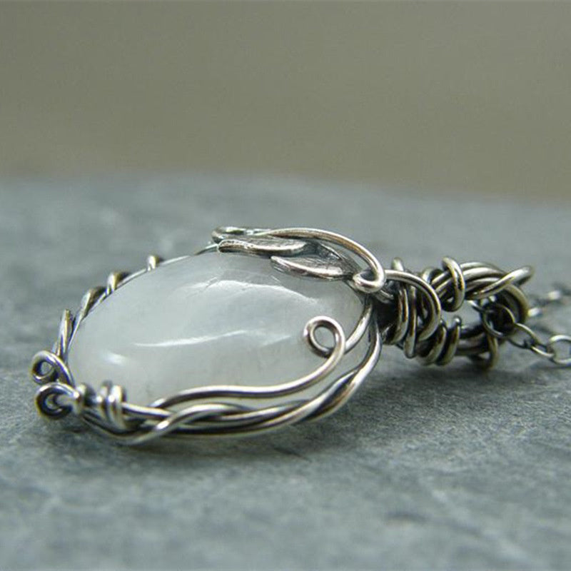 Silberner Drahtanhänger mit weißem Edelstein, handgefertigter Schmuck, elegantes Design.