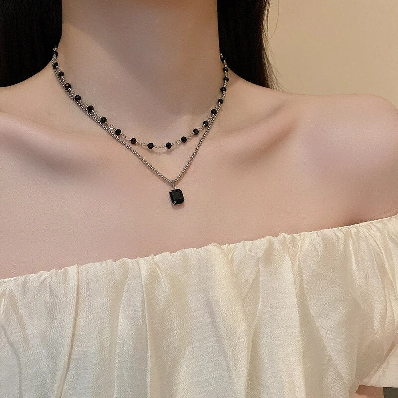 Doppelte Halskette mit schwarzem Anhänger, Damenmode, eleganter Schmuck, Off-Shoulder-Kleid.