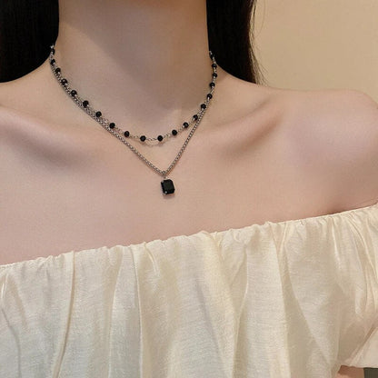 Doppelte Halskette mit schwarzem Anhänger, Damenmode, eleganter Schmuck, Off-Shoulder-Kleid.