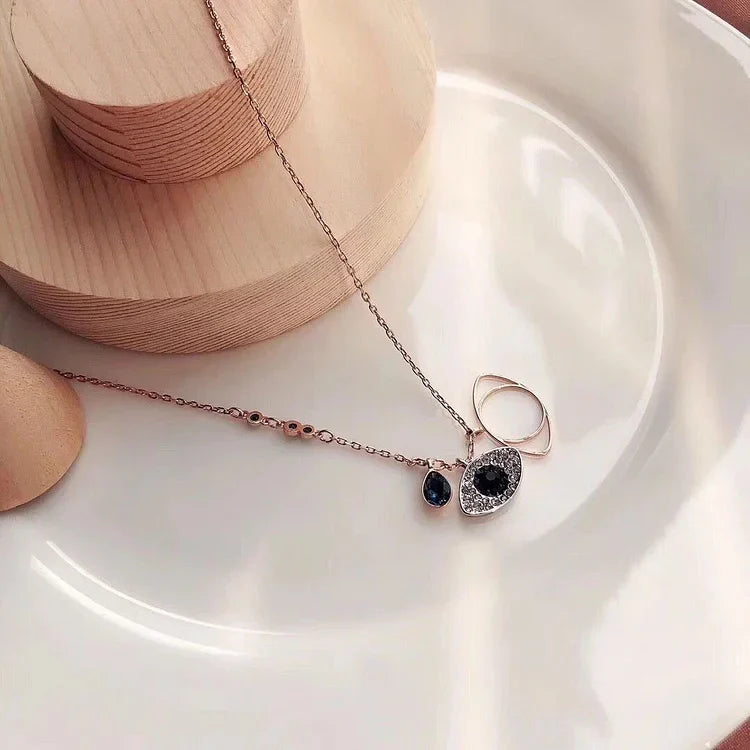 Goldene Halskette mit blauem Anhänger und Ring auf weißem Teller, Schmuckdesign elegant.