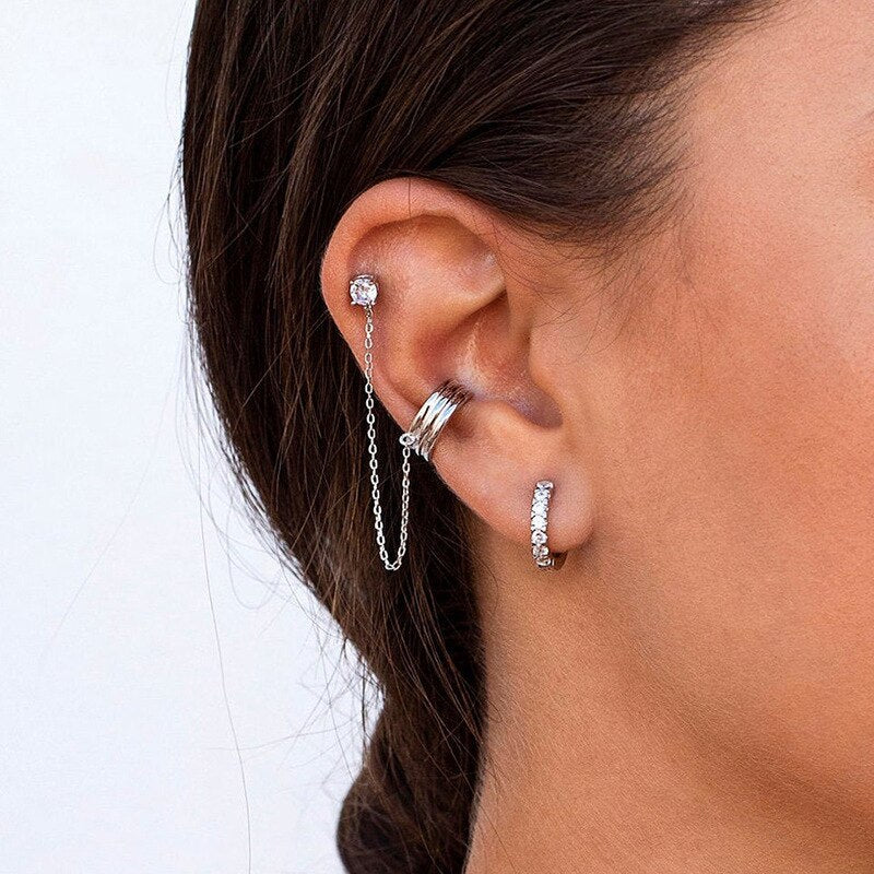 Ohrringe Set Silber mit Kette und Kristallen am Ohr einer Frau, modischer Schmuck.