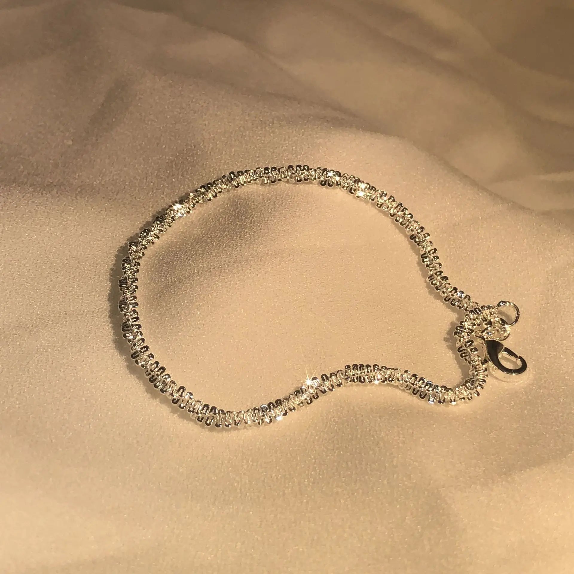Silbernes Armband mit Zirkonia-Steinen auf beigem Stoff, funkelnd, elegantes Schmuckstück.