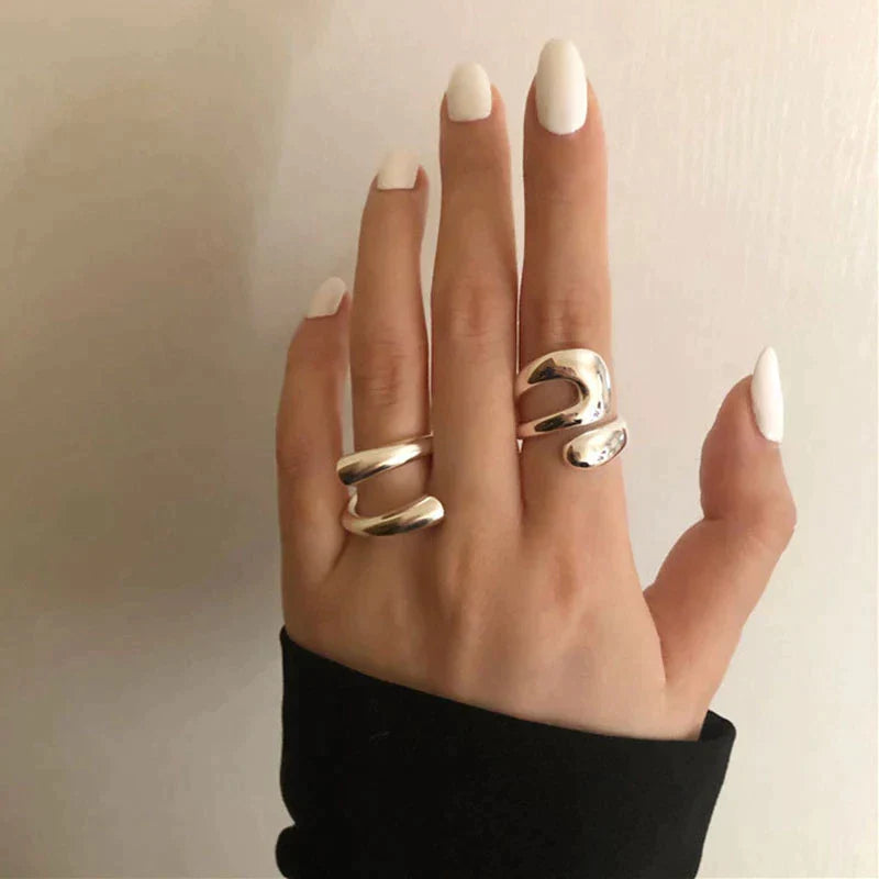 Silberne Statement-Ringe an Hand mit weiß lackierten Nägeln, modisches Accessoire, Damenmode.