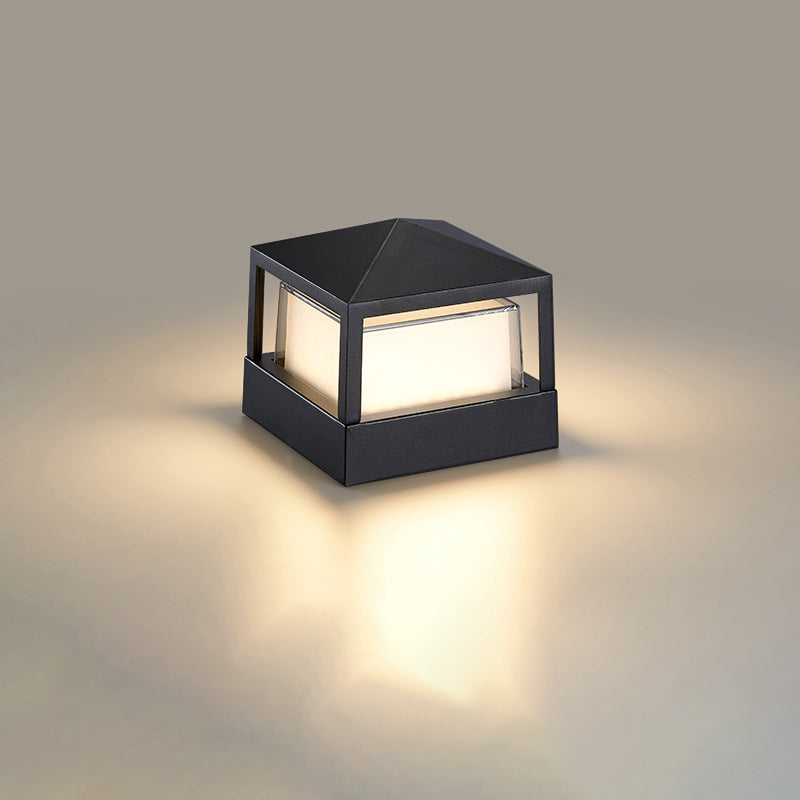 Firkantet sort lampe med pyramideformet låg og varmt lys, set skråt fra siden på neutral baggrund. 10