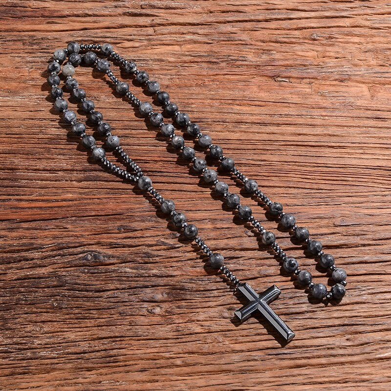 Schwarze Perlenkette mit Kreuzanhänger auf Holzoberfläche, modisches Accessoire, Unisex.