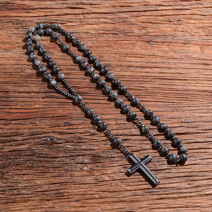 Schwarze Perlenkette mit Kreuzanhänger auf Holzoberfläche, modisches Accessoire, Unisex.