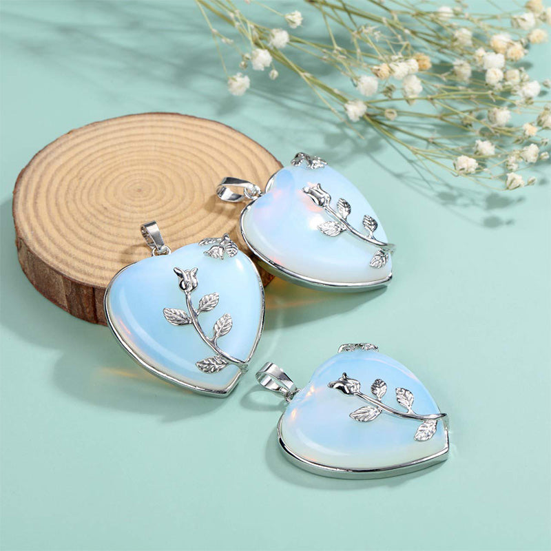 Herzförmiger Opal-Anhänger mit Silberzweig, eleganter Schmuck auf Holzscheibe, hellblau.