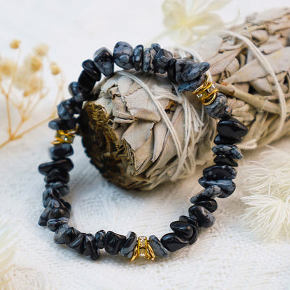 Schwarzes Edelsteinarmband mit goldenen Akzenten auf weißem Hintergrund, Schmuck, Modeaccessoire.